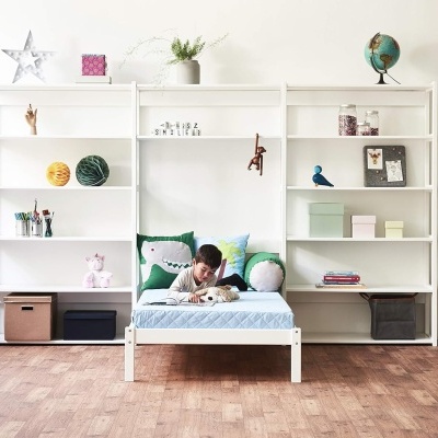 Quarto infantil com cama branca e estantes brancas com decoração e brinquedos
