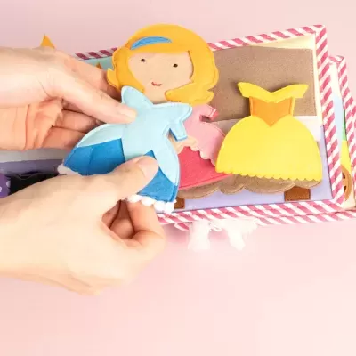 Boneca de feltro com vestidos de feltro coloridos e mãos segurar boneca
