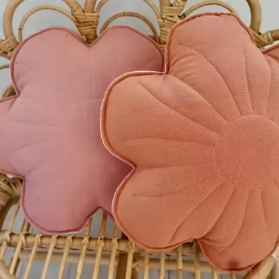 Duas almofadas florais rosa claro e salmão num banco de vime