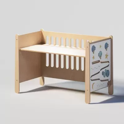 Berço infantil de madeira clara com painel de atividades e desenhos de estrelas e luas.