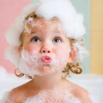 Criança com espuma de sabão na cabeça e rosto durante banho