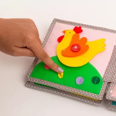 Livro de pano infantil com galinha amarela e botões coloridos