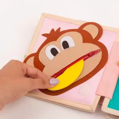 Livro de tecido para crianças com rosto de macaco e fecho vermelho na boca