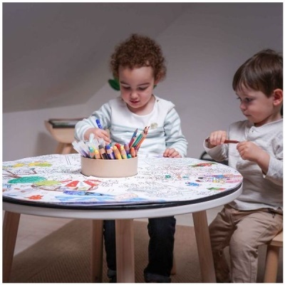 Mesa redonda para crianças com tampo para colorir e canetas coloridas no centro com duas crianças a pintar