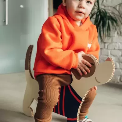 Criança sentada em cadeira de brincadeira em forma de cão feita de material corrugado.