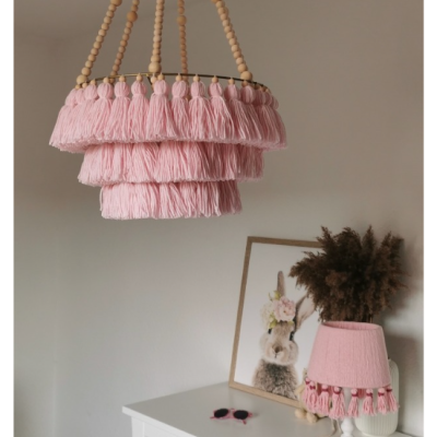 Candeeiro de tecto e luminária de mesa rosa com franjas e cordões de madeira em divisão com cómoda branca