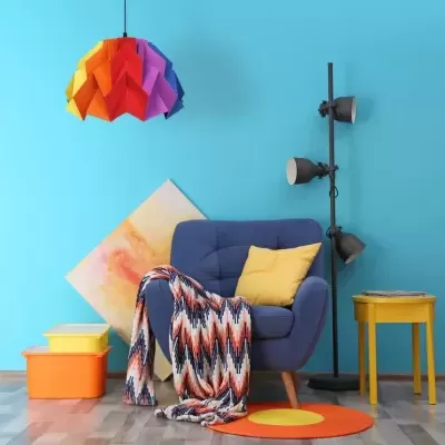 Canto moderno com cadeira azul, manta colorida, almofada amarela, mesa amarela, abajur triplo e luminária de teto colorida