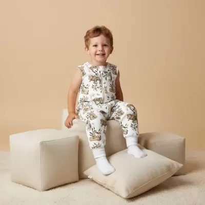 Criança com pijama branco estampado sentada em almofadas bege