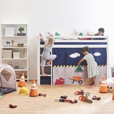 Quarto infantil com cama alta de madeira branca e decoração temática de construção.