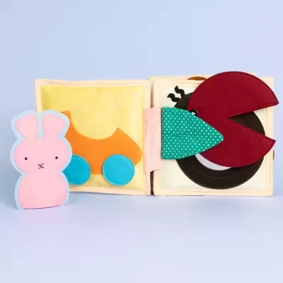 Livro de tecido para bebés com figuras coloridas em feltro e tecido de padrão bolinhas.