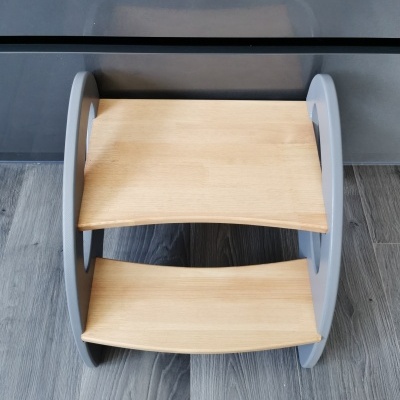 Escadote de criança em madeira clara e cinzenta colocado em chão de madeira escura