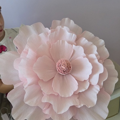 Flor decorativa grande em papel crepom rosa claro com várias camadas de pétalas.