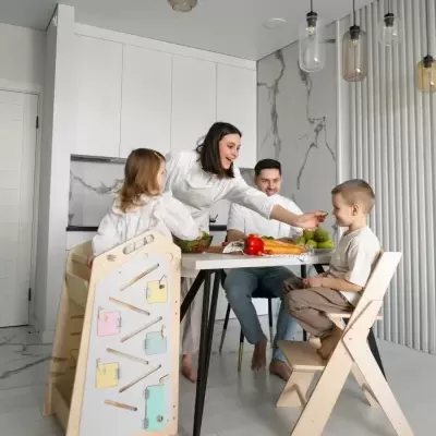 Família na cozinha moderna com cadeiras infantis de madeira e mesa com alimentos.