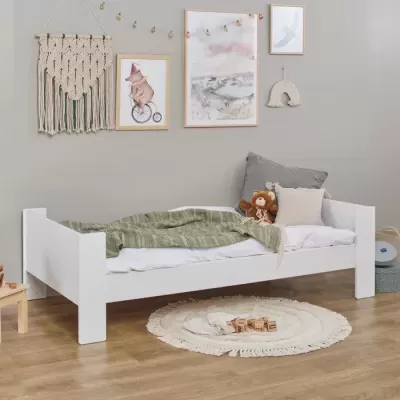 Cama infantil branca com decoração e tapete redondo bege