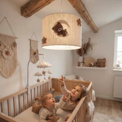 Abajur de tecto infantil com ursinho, lua e estrelas em tons bege e castanho, berço em madeira, macramé na parede e duas crianças no berço.