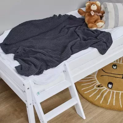 Cama infantil branca com manta cinza e peluche castanho