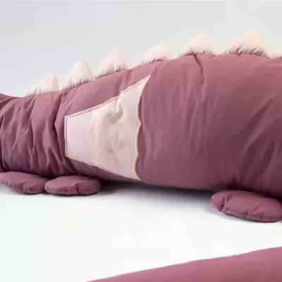 Almofada de peluche rosa com formato de dinossauro