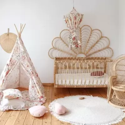 Quarto infantil com berço de vime, tenda de tecido floral, cadeira de vime e tapete redondo branco