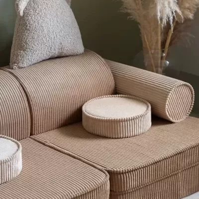 Sofá de veludo cotelê com almofada em formato de cabeça de urso e decoração com folhas secas