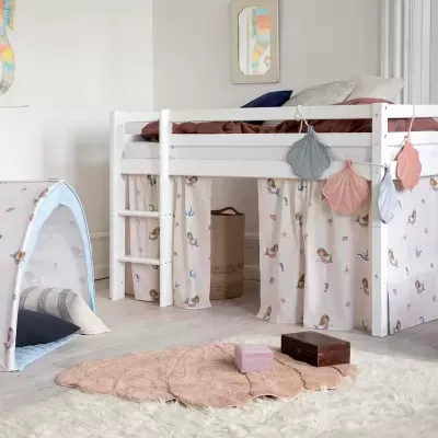 Cama alta branca para criança com cortinas de sereias e tenda infantil azul em quarto decorado.