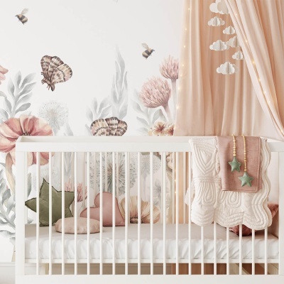 Berço branco de madeira com almofadas e manta decorativa, papel de parede floral com borboletas e cortina cor de rosa