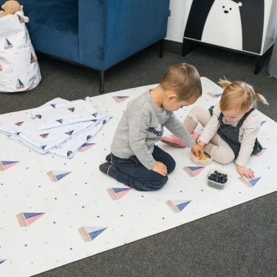 Tapete infantil branco com veleiros coloridos e crianças a brincar.