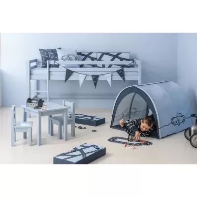 Quarto infantil com cama alta branca, tenda azul, mesa e cadeiras brancas, padrões de carros e estradas, criança a brincar no chão