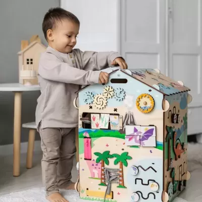 Criança a brincar com casinha de brinquedo em madeira com atividades educativas coloridas.