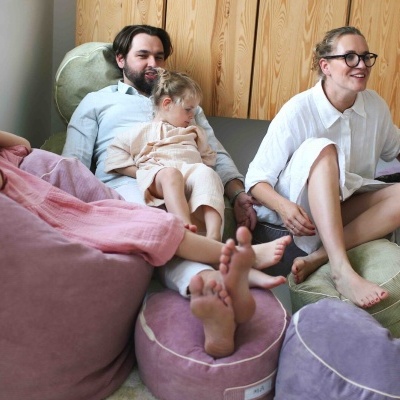 Pufes e almofadas de veludo coloridas com pessoas sentadas num ambiente interior