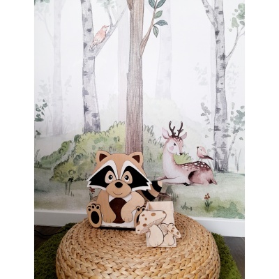 Decoração infantil de guaxinim e cogumelos em madeira sobre almofada de palha e papel de parede com floresta