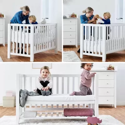 Berço branco de madeira em quarto infantil com crianças e cómoda