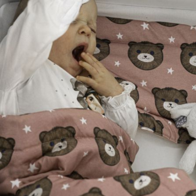 Colcha e almofada com estampado de ursinhos castanhos e estrelas brancas em tecido cor de rosa para cama de criança