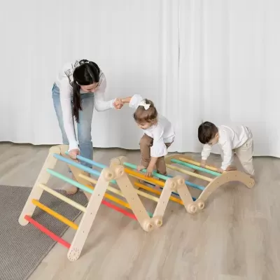 Estrutura de escalada de madeira com barras coloridas usada por crianças e mulher em quarto com cortinas brancas