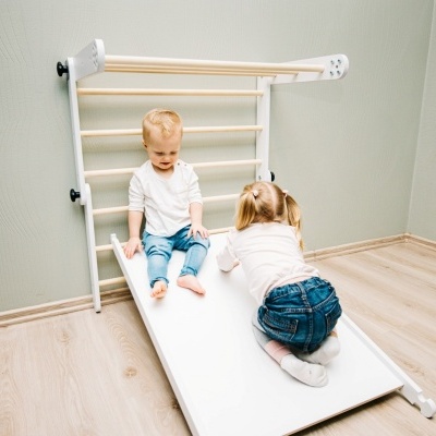 Escorrega infantil branco com estrutura de madeira clara num quarto com duas crianças a brincar