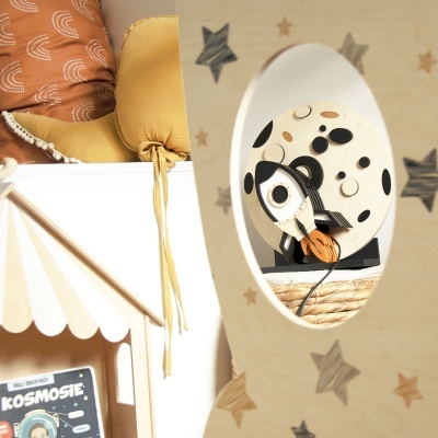 Espelho decorativo infantil em madeira com estrelas refletindo brinquedo de madeira e plástico.