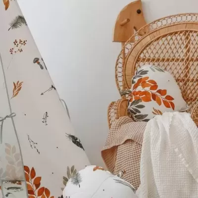 Cadeira em rattan com almofadas e tenda de tecido com padrão botânico