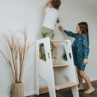 Escada de aprendizagem branca e madeira com duas crianças a parede branca e vaso com ramos secos