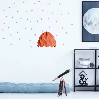 Espaço interior com almofada azul, luminária laranja, estante preta com objetos decorativos e quadro da lua