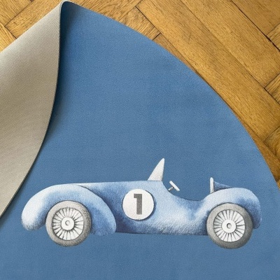 Tapete redondo azul com desenho de carro de corrida e chão de madeira