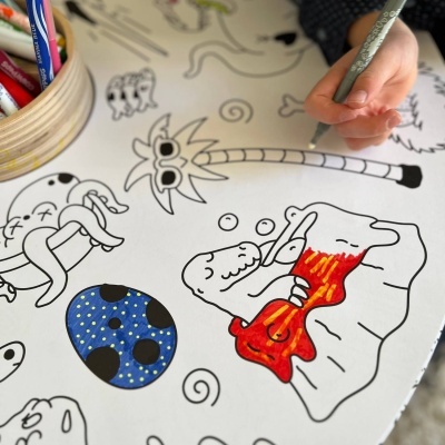 Criança a pintar desenhos em papel branco com canetas coloridas