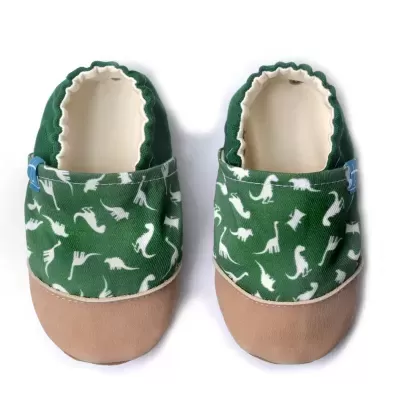 Sapatilhas infantis verdes com padrão branco de dinossauros e biqueira em camurça bege