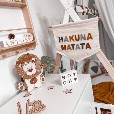 Quarto infantil com decoração temática de leão e mensagem Hakuna Matata em bandeira de tecido
