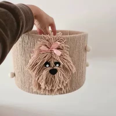 Cesta redonda de tecido bege com decoração de cão felpudo rosa