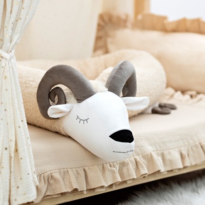 Cama de criança com almofada de carneiro e almofadas creme