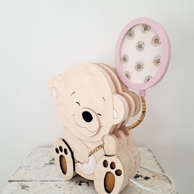 Lâmpada de mesa em madeira com formato de urso e balão rosa decorado com flores.