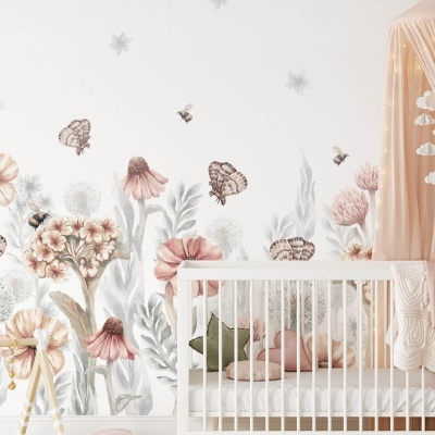 Berço branco com colcha e manta rosa sob baldaquino bege junto a parede com autocolantes de flores e borboletas