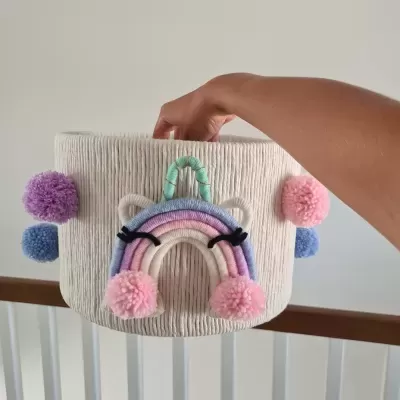 Cesto de tecido branco com arco-íris colorido e pompons decorativos