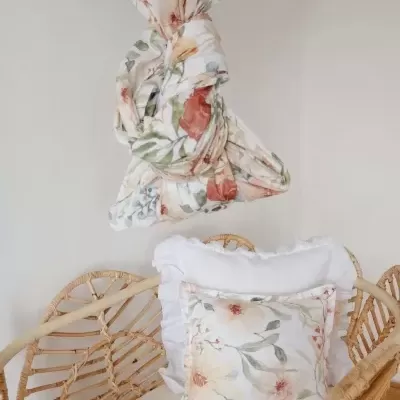 Cortina e almofada florais num ambiente com cadeira de rattan