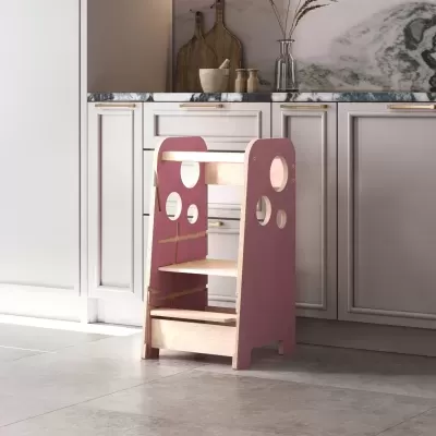 Escada infantil em madeira natural e rosa com orifícios circulares, em cozinha com armários brancos e tampo mármore