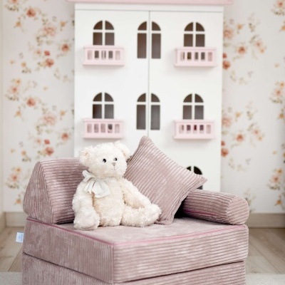 Poltrona infantil rosa de veludo cotelê com urso de pelúcia branca e móvel casinha ao fundo